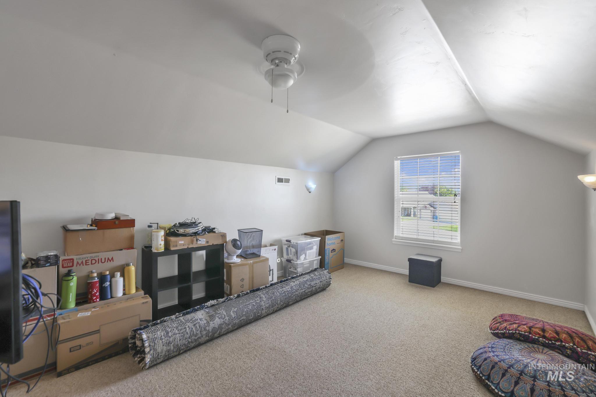Bonus room featuring carpet flooring, lofted ceiling, and a ceiling fan