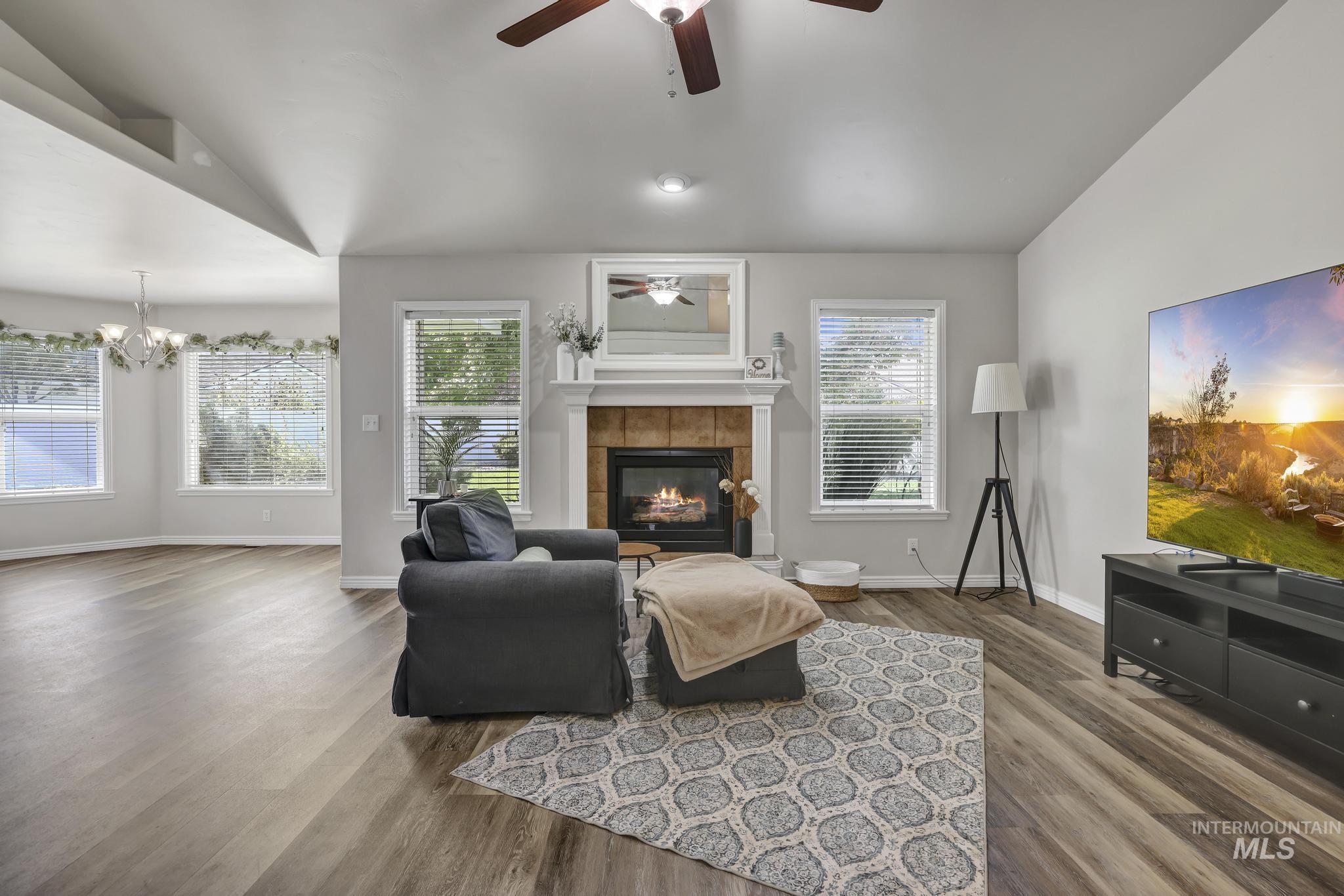 Living area with wood finished floors, a tile fireplace, and ceiling fan