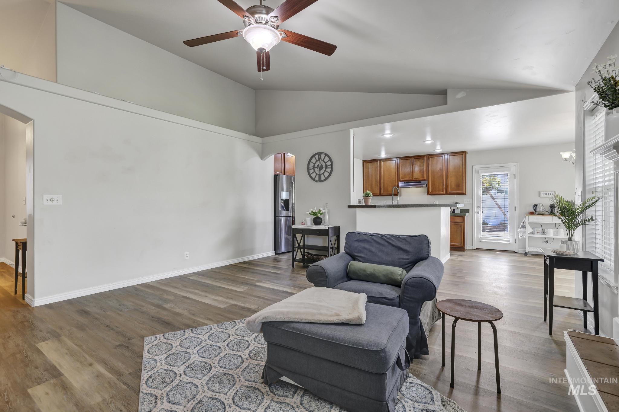 Living room with arched walkways, dark wood-type flooring, a ceiling fan, and high vaulted ceiling