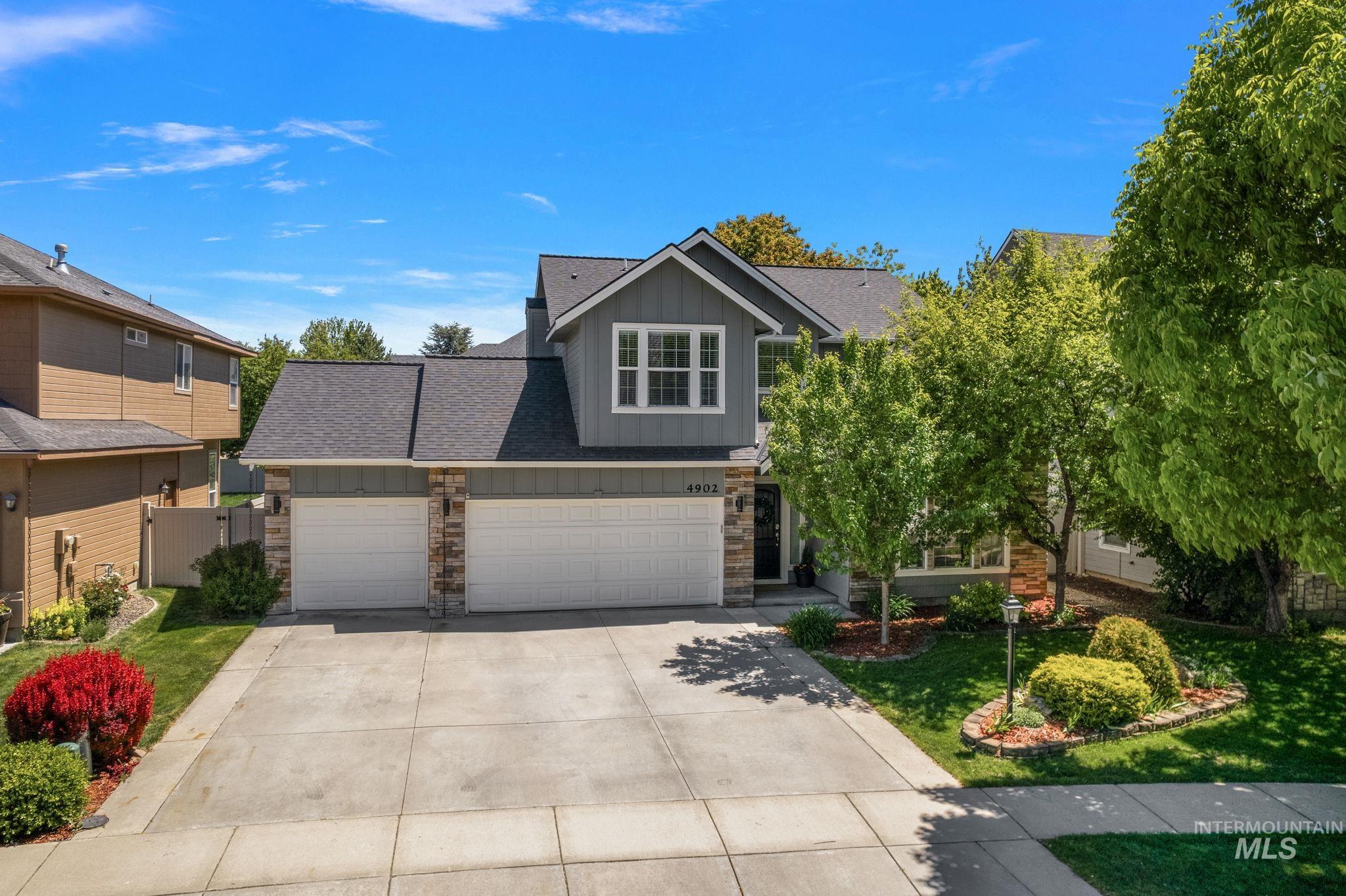 View of front of home featuring board and batten siding, concrete driveway, stone siding, an attached garage, and roof with shingles