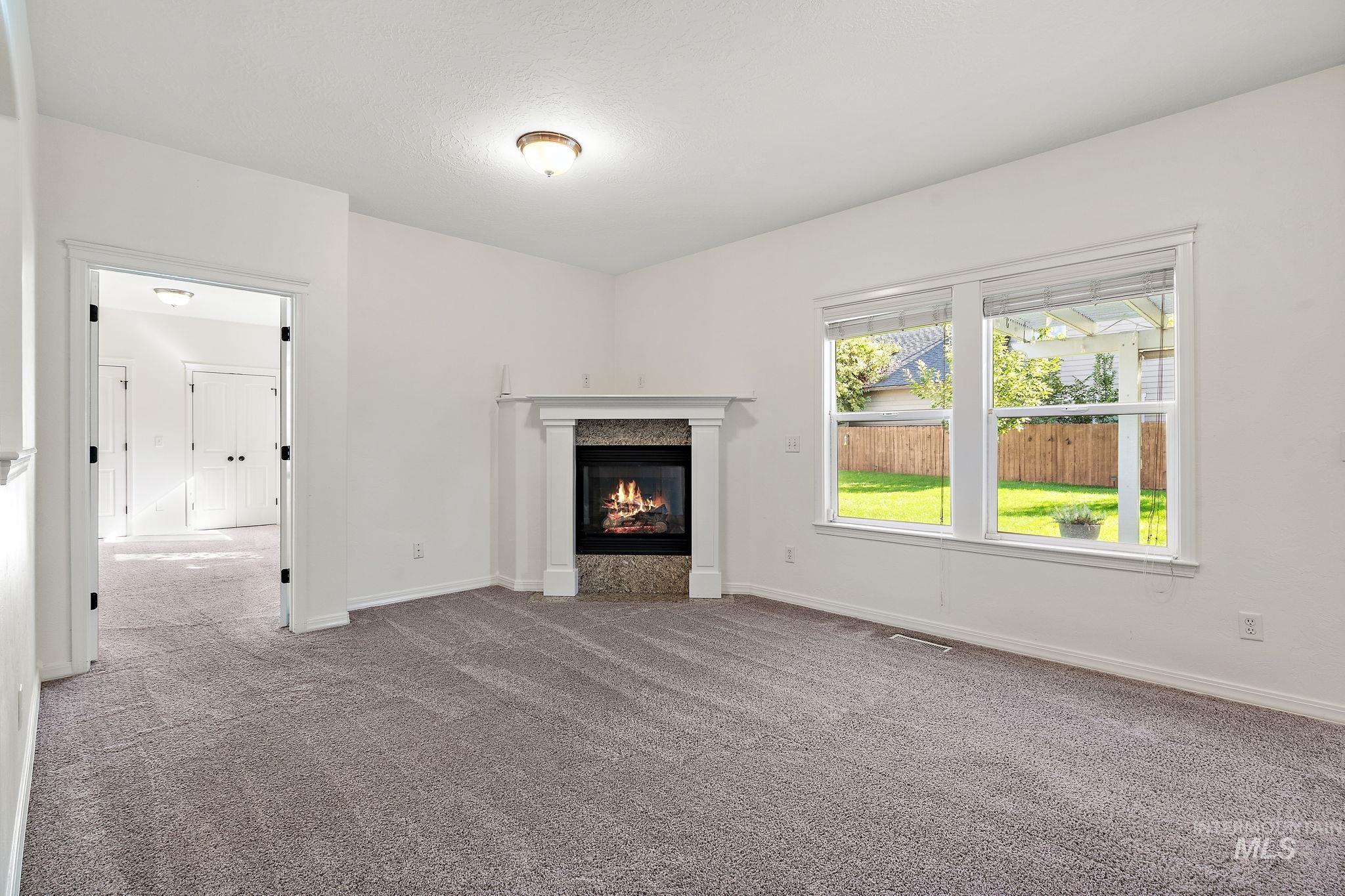 Unfurnished living room with carpet flooring and a premium fireplace