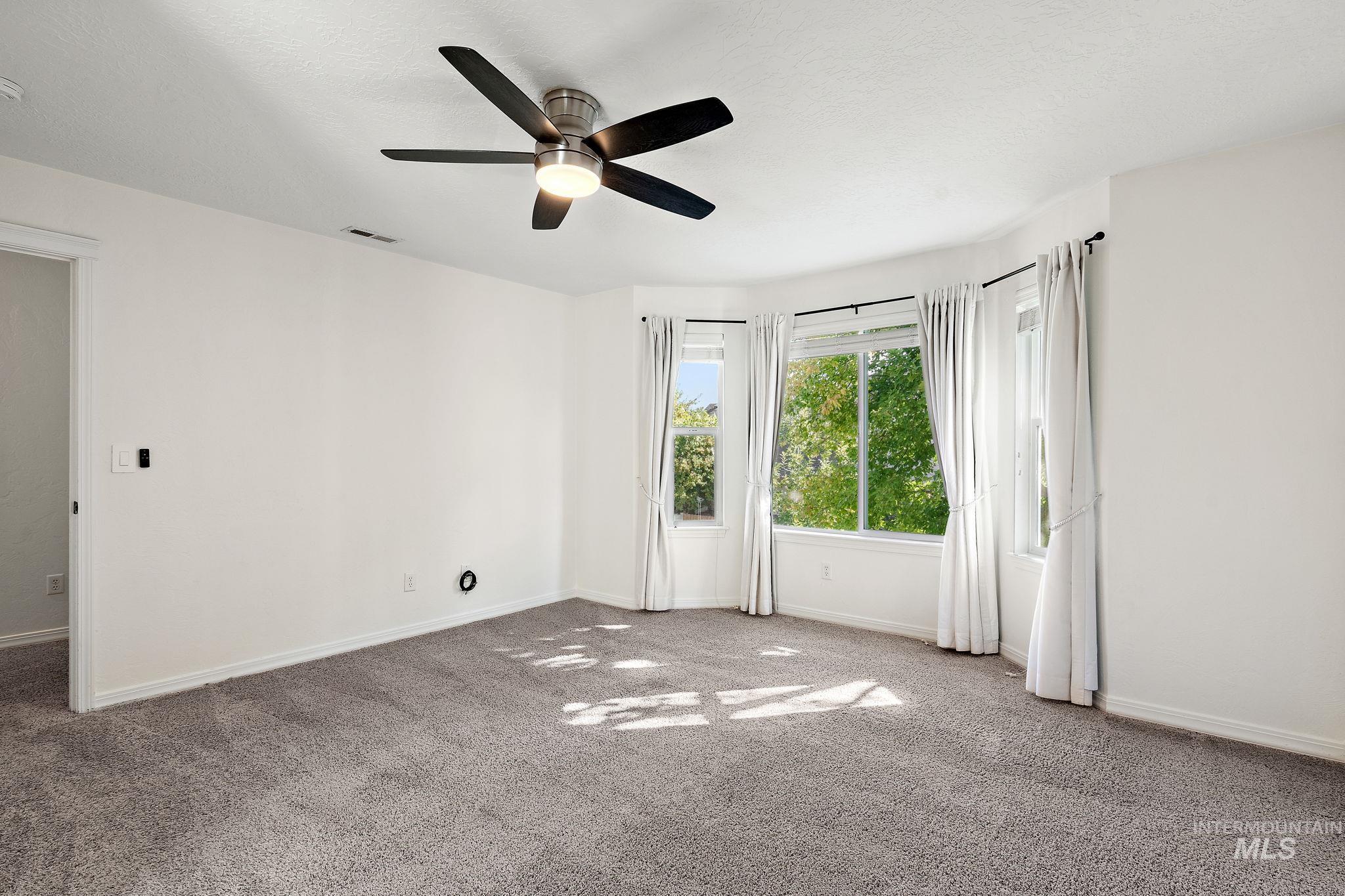 Empty room with carpet and a ceiling fan