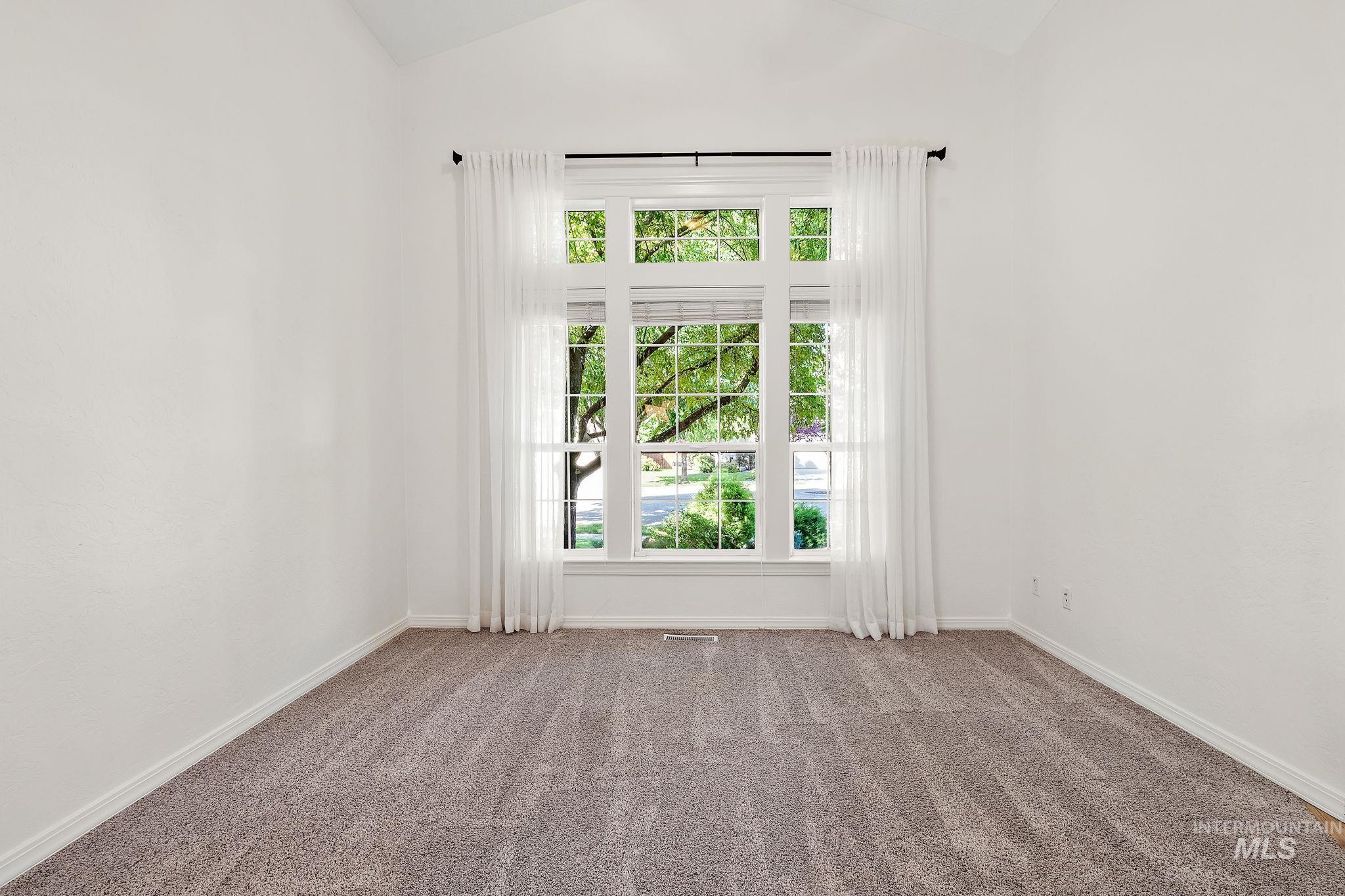 Empty room featuring vaulted ceiling and carpet