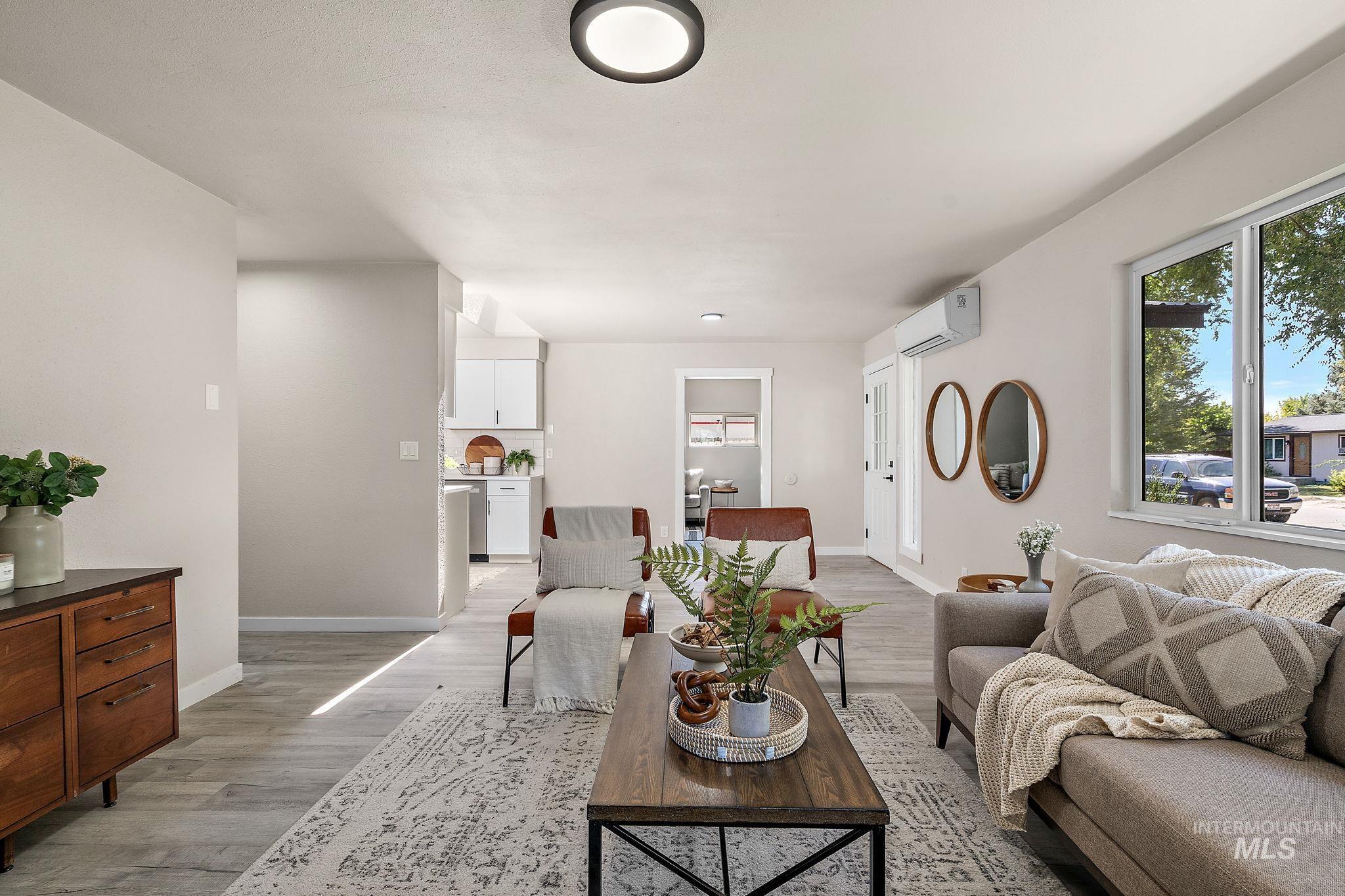 Living room with light wood-style flooring and an AC wall unit