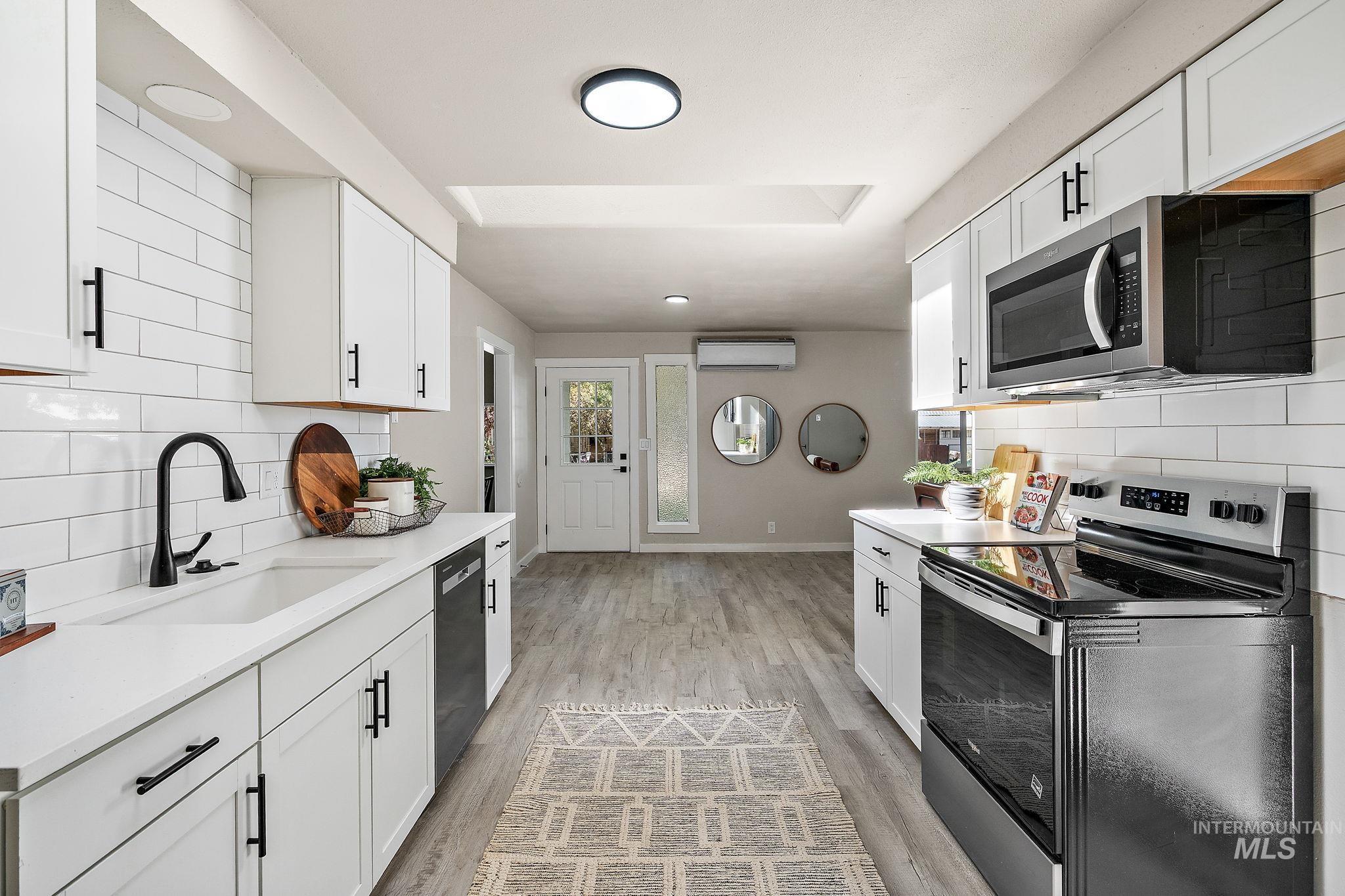 Kitchen with tasteful backsplash, stainless steel appliances, and white cabinetry