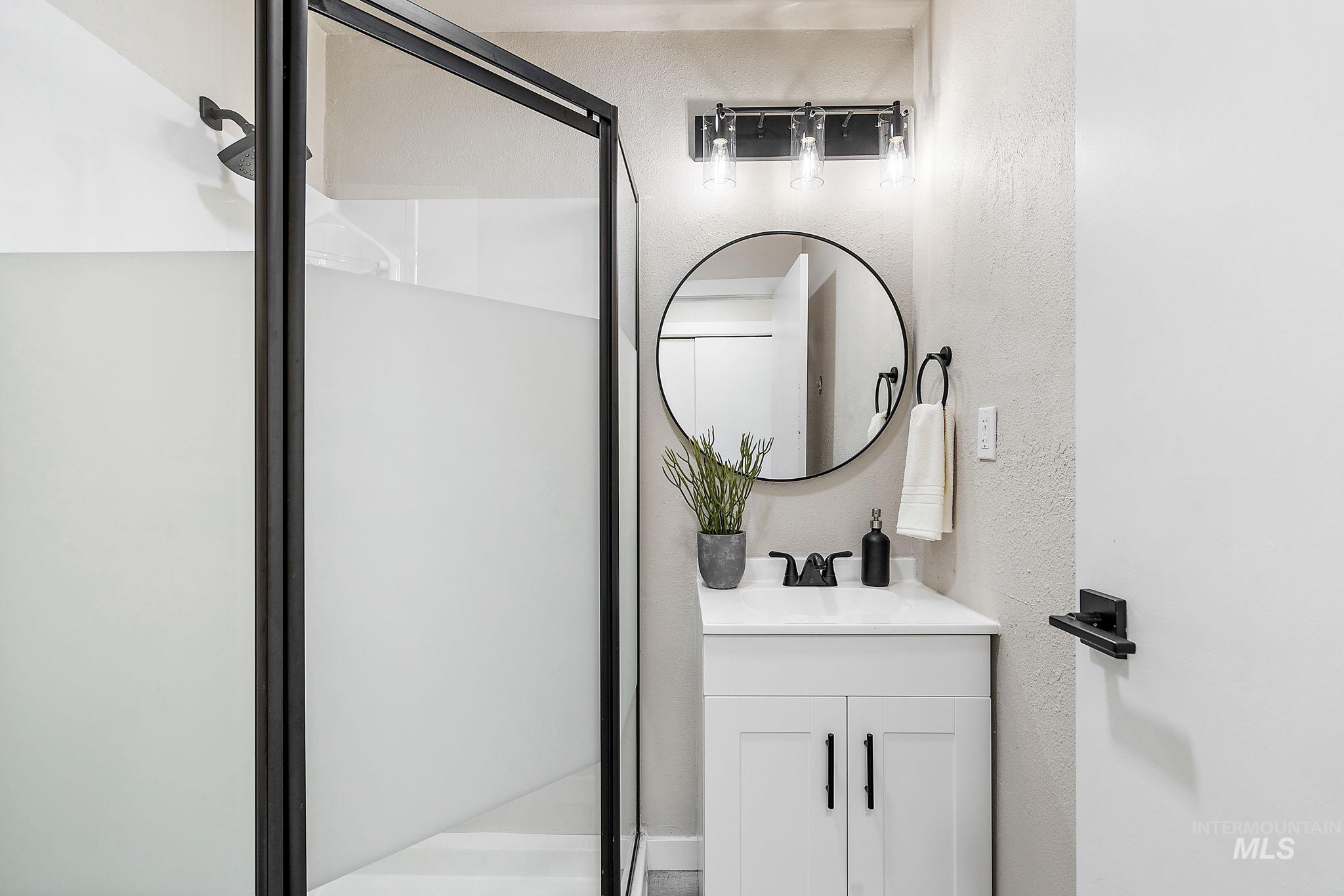 Bathroom with a shower stall, vanity, and a textured wall