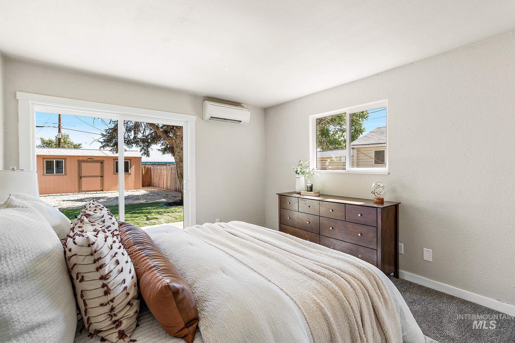 Carpeted bedroom featuring access to exterior, a wall unit AC, and a textured wall