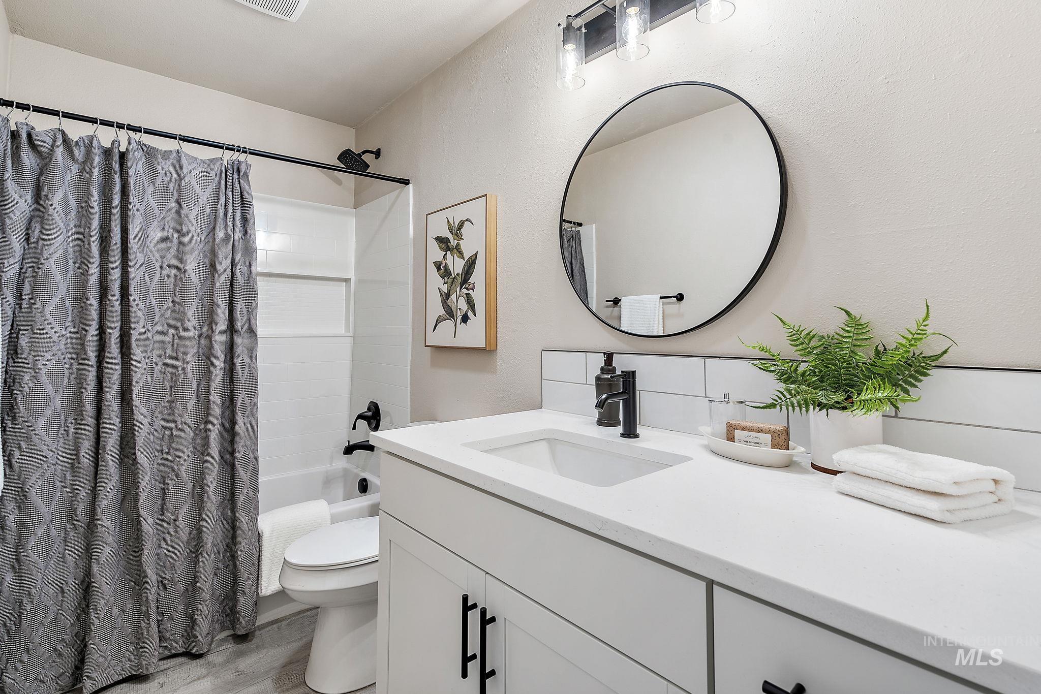 Bathroom with vanity, shower / bath combo, and light wood-type flooring