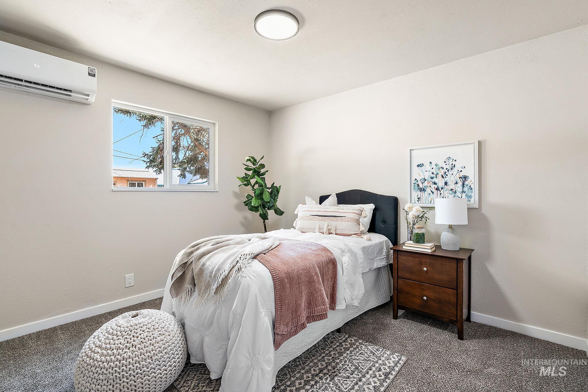 Bedroom with carpet flooring and a wall mounted air conditioner