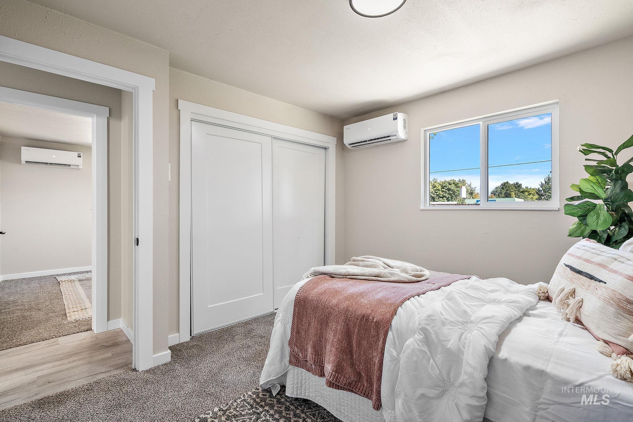 Bedroom with carpet floors, a closet, and a wall mounted AC