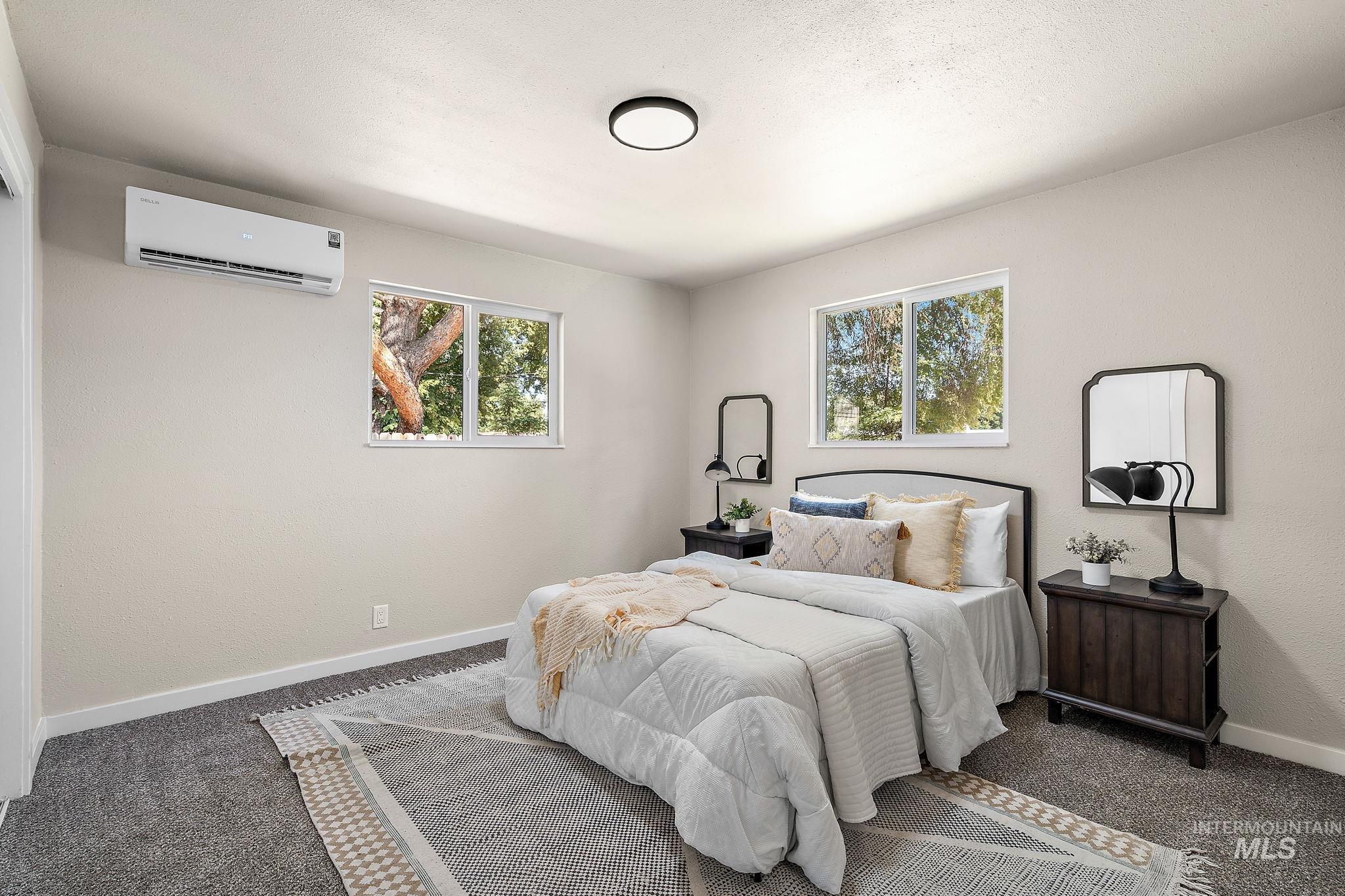 Carpeted bedroom featuring baseboards and a wall unit AC