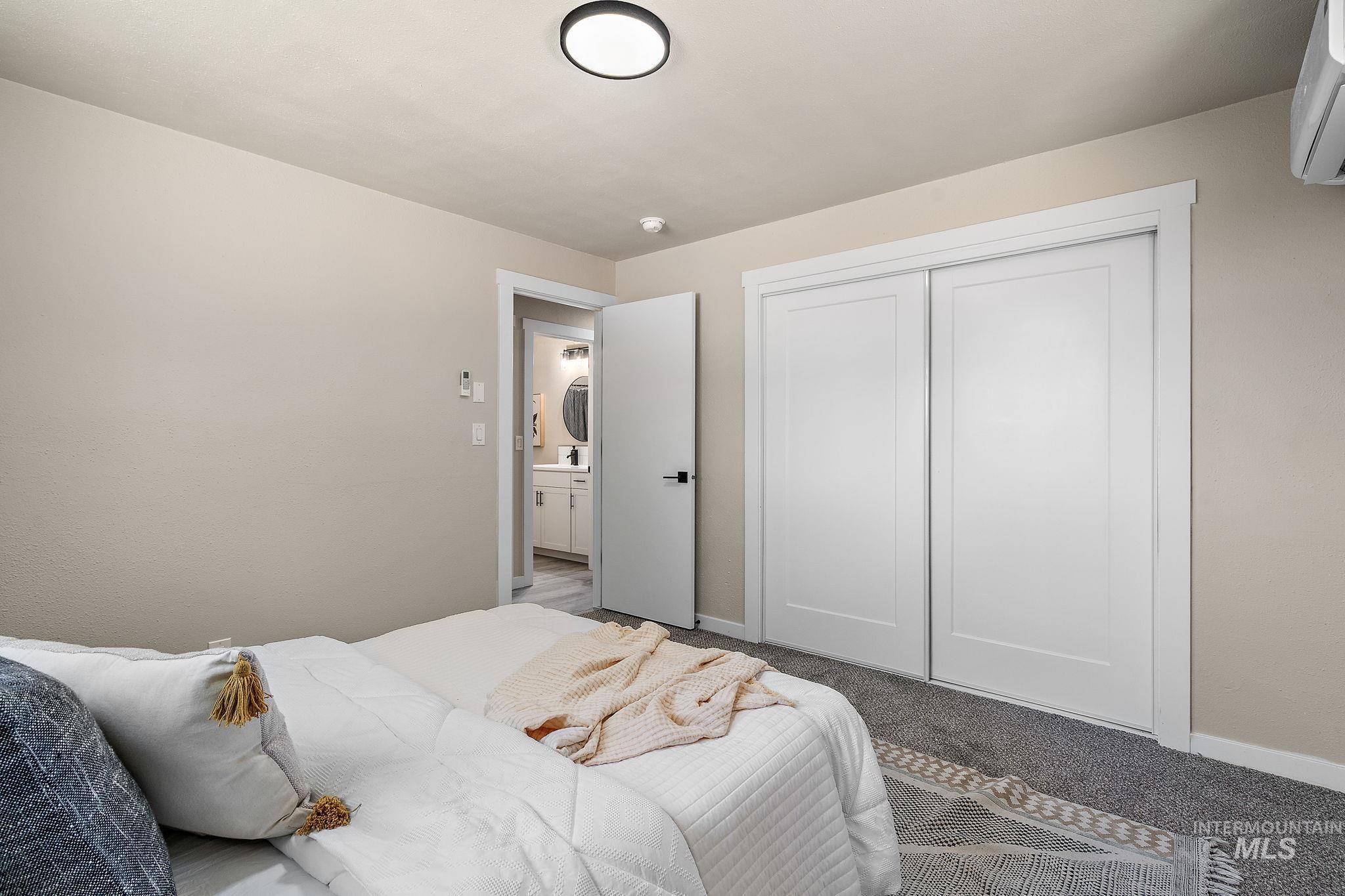 Bedroom with carpet floors, a closet, and a wall mounted air conditioner