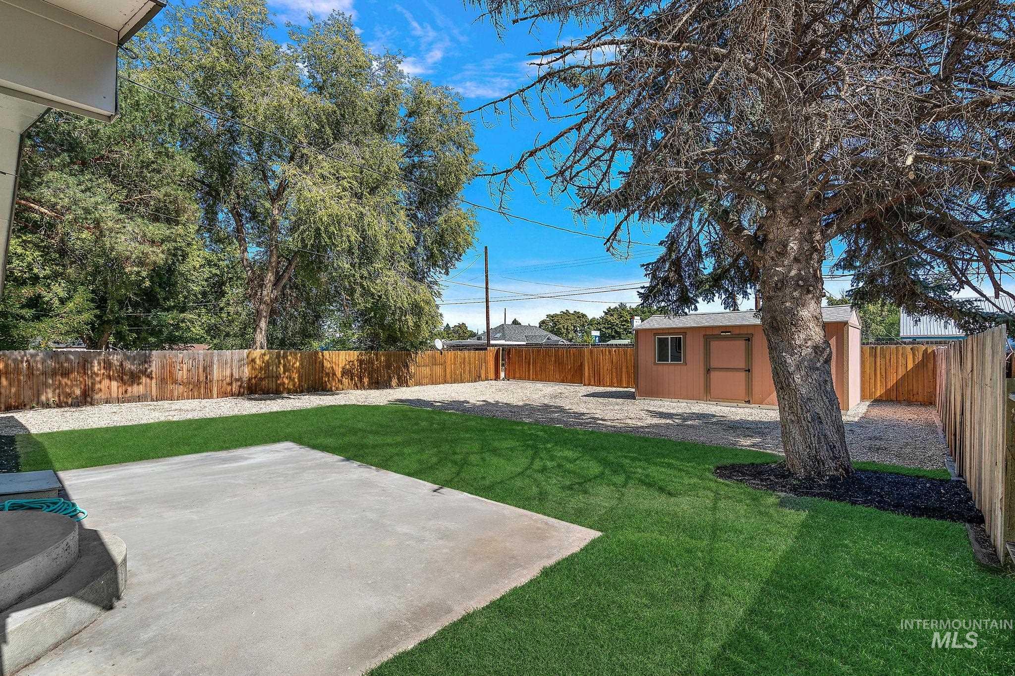 Fenced backyard featuring a patio area and a shed