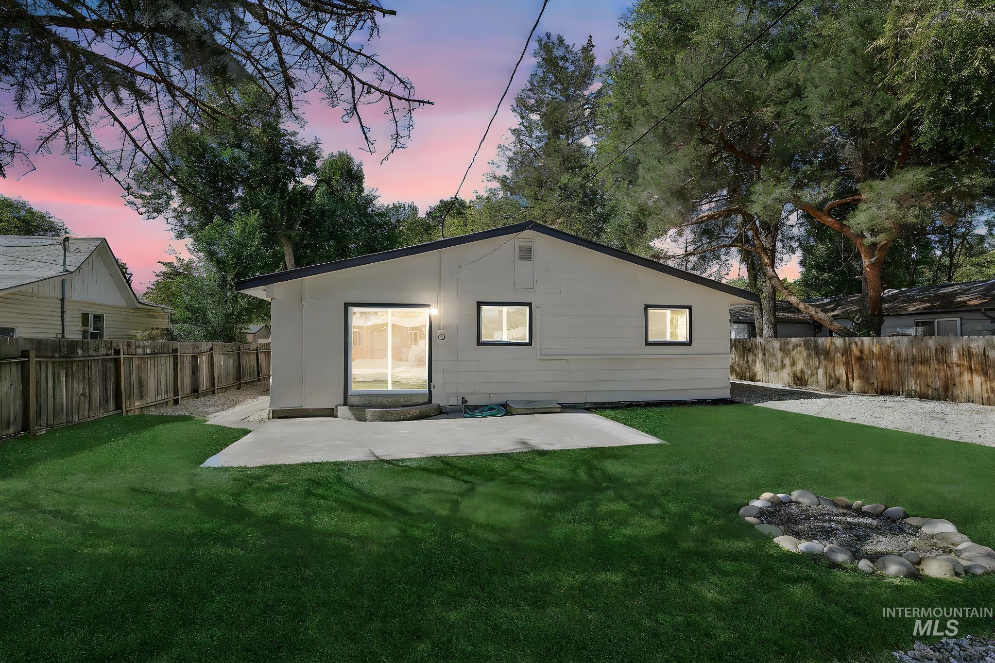Back of house at dusk with a patio area and a fenced backyard