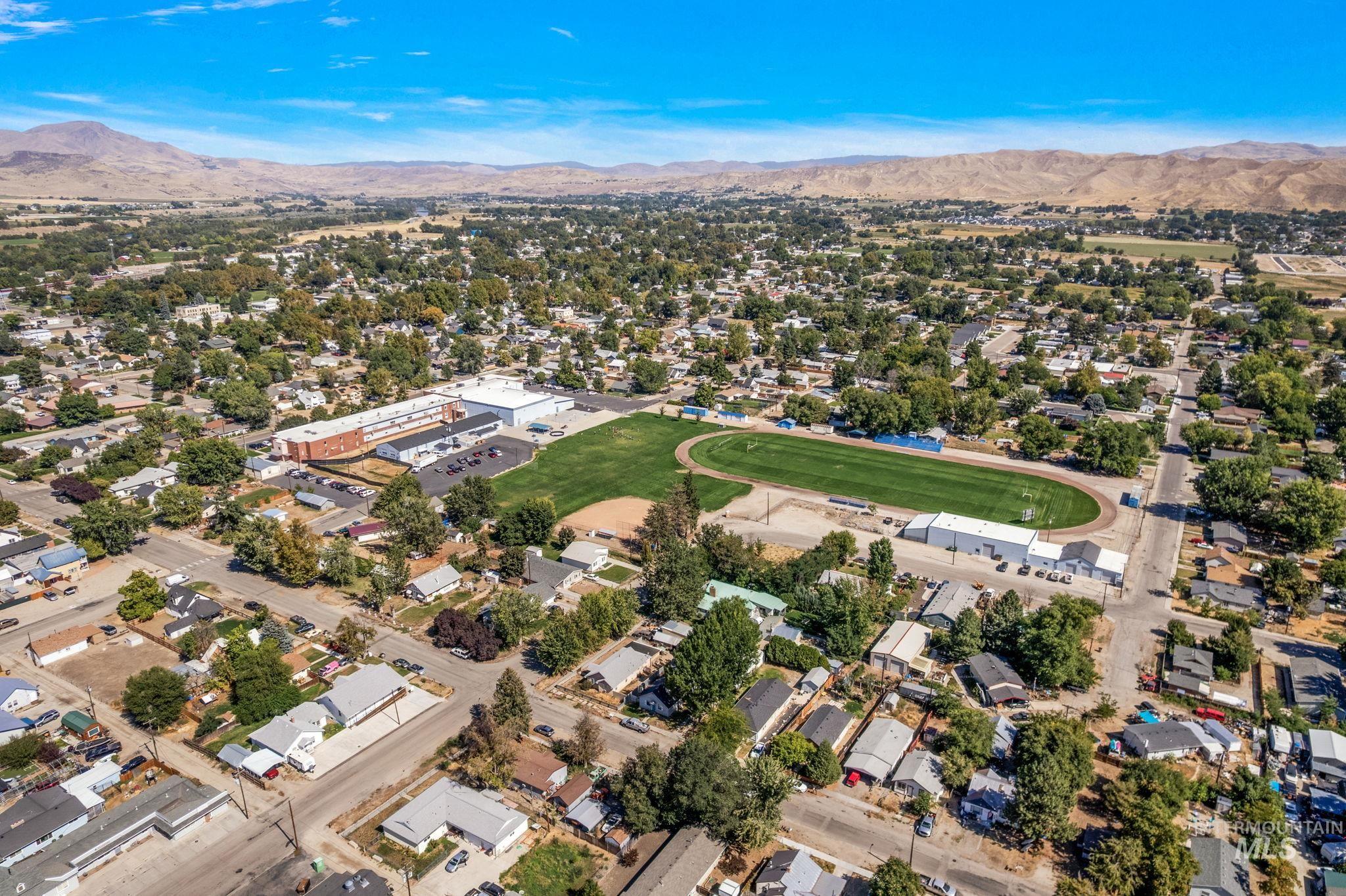 Aerial view of property and surrounding area with a mountainous background and nearby suburban area