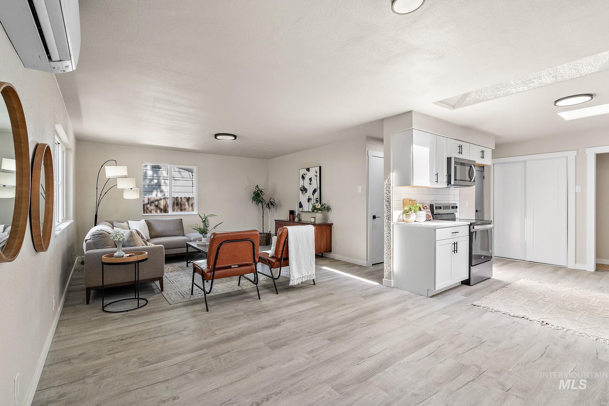 Living room with light wood-style floors and a wall mounted air conditioner