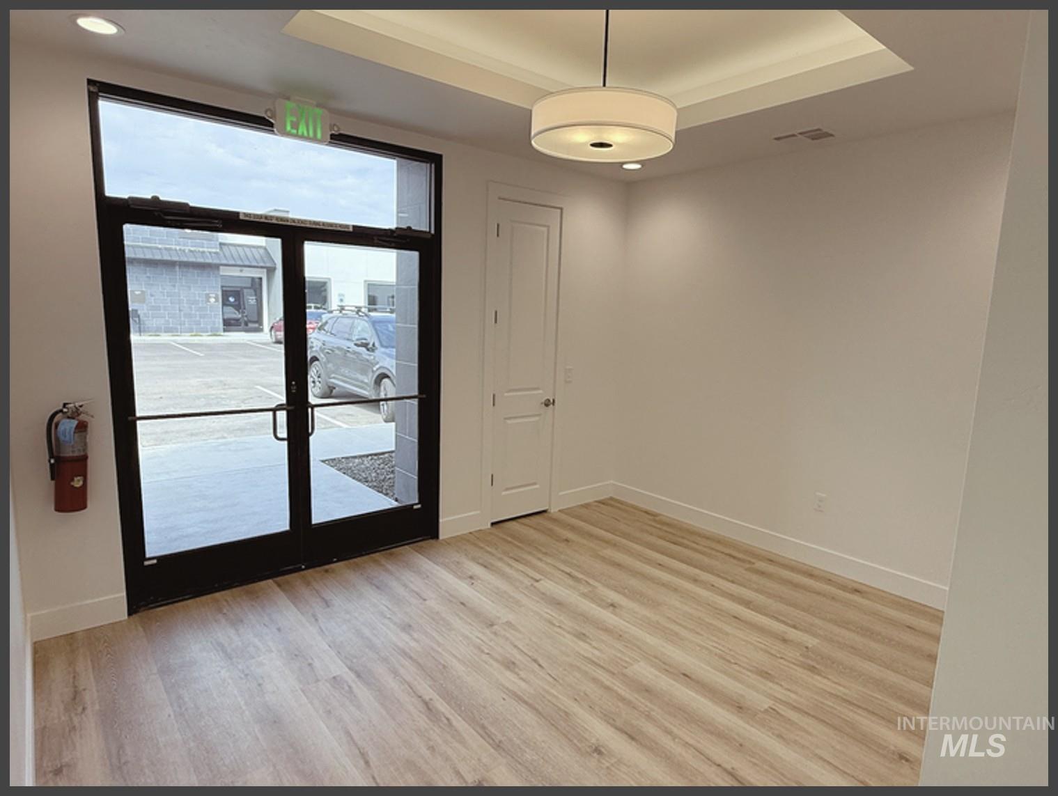 Unfurnished room with a tray ceiling and light wood-style flooring