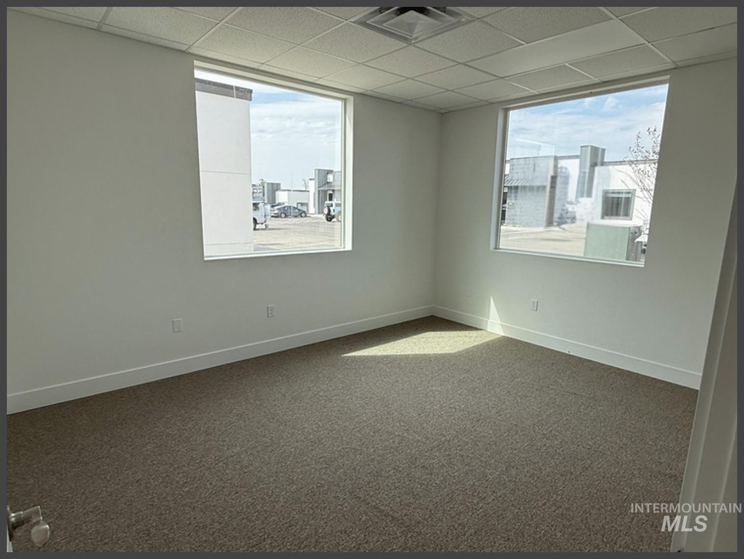 Unfurnished room featuring carpet floors, healthy amount of natural light, and a paneled ceiling