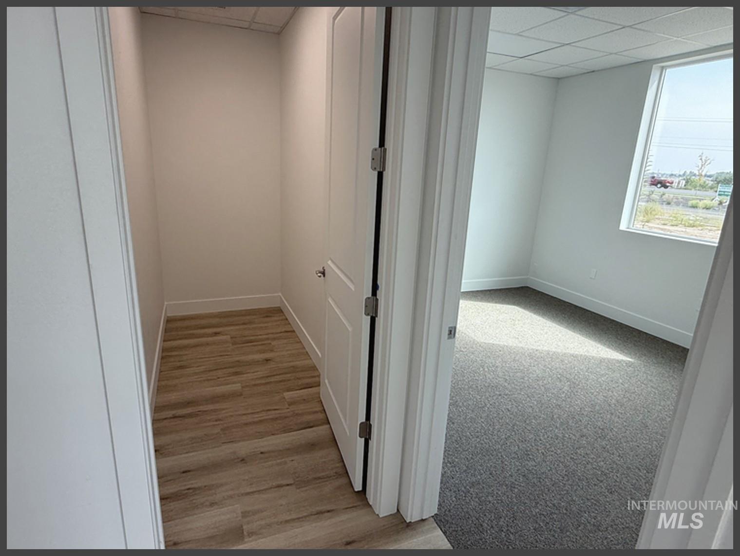 Corridor with a paneled ceiling and light wood finished floors