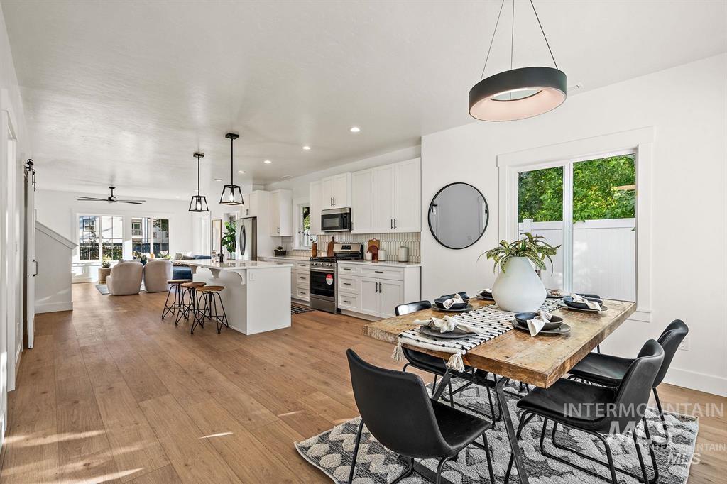 Dining space featuring light wood-style floors, ceiling fan, recessed lighting, and a barn door