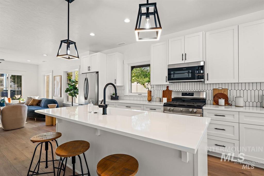 Kitchen featuring white cabinetry, open floor plan, a kitchen breakfast bar, and recessed lighting