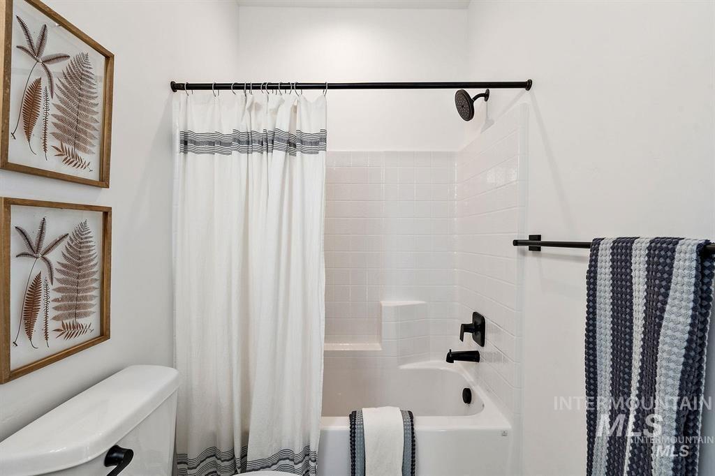 Bathroom featuring shower / bath combination with curtain and toilet