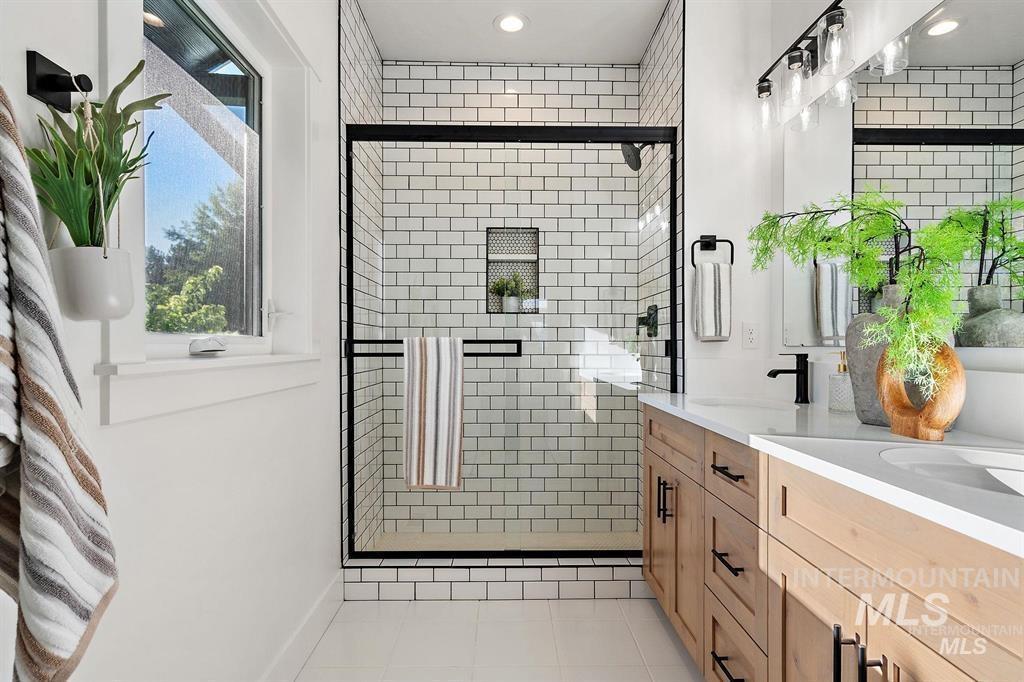 Bathroom with a shower stall, light tile patterned floors, double vanity, and recessed lighting