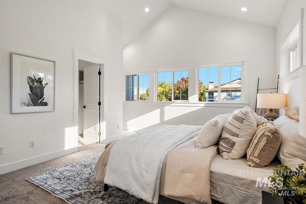 Carpeted bedroom featuring multiple windows, high vaulted ceiling, and recessed lighting