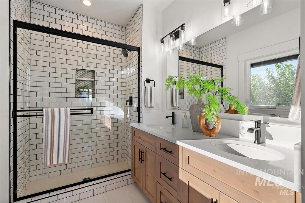 Bathroom featuring double vanity, a shower stall, light tile patterned floors, and recessed lighting