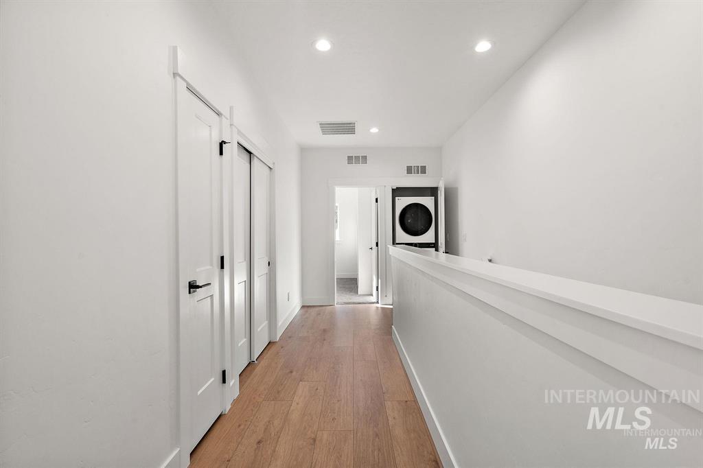 Hall with light wood-style floors, recessed lighting, and stacked washing machine and dryer