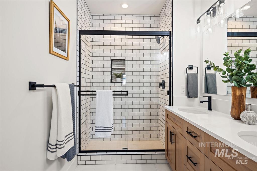 Bathroom featuring a stall shower, double vanity, and light tile patterned floors