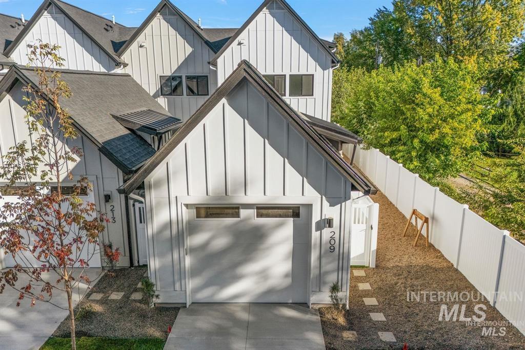 Modern inspired farmhouse featuring board and batten siding, concrete driveway, roof with shingles, and a garage