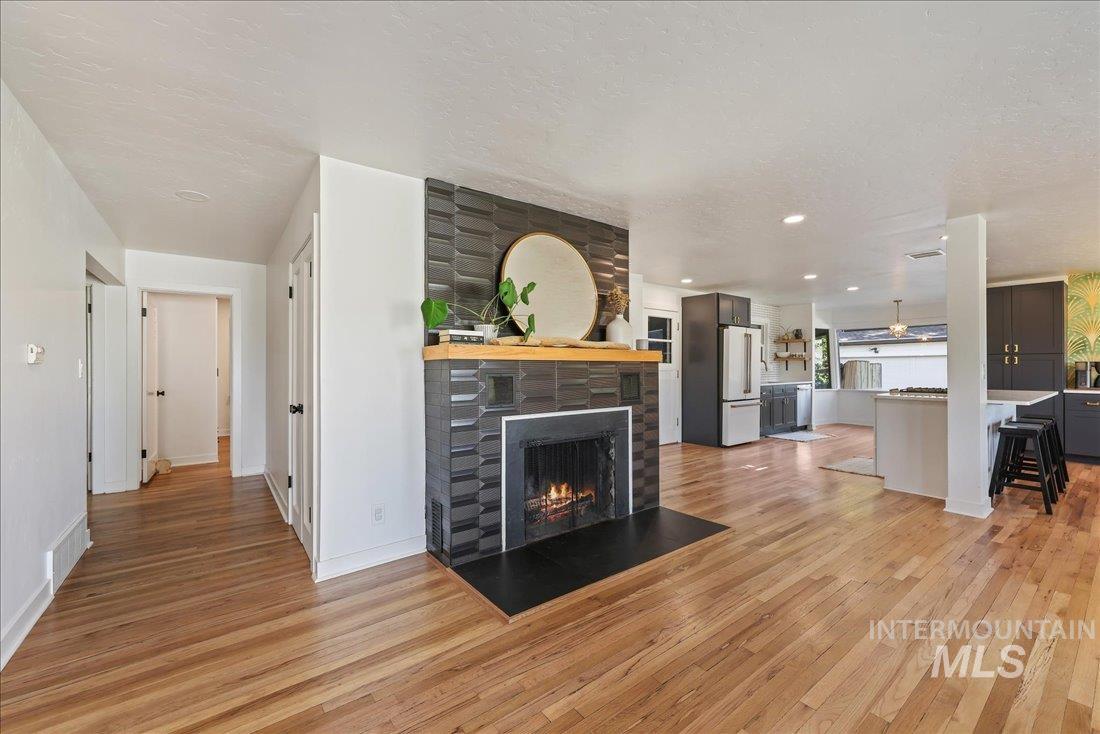 Living room featuring a lit fireplace, light wood finished floors, a textured ceiling, and recessed lighting
