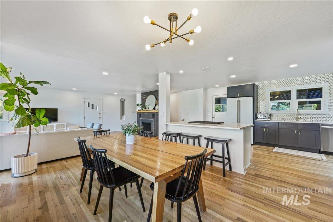 Dining area with a fireplace, light wood-style flooring, recessed lighting, and a chandelier
