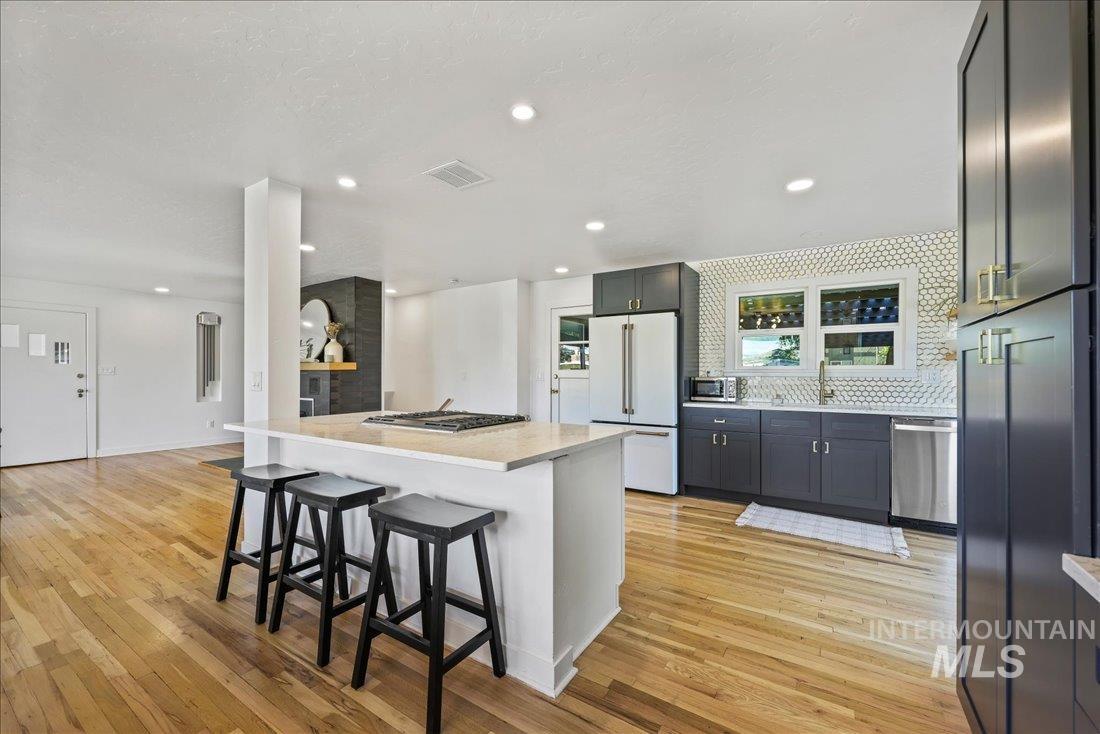 Kitchen with a kitchen breakfast bar, appliances with stainless steel finishes, a center island, light wood finished floors, and recessed lighting