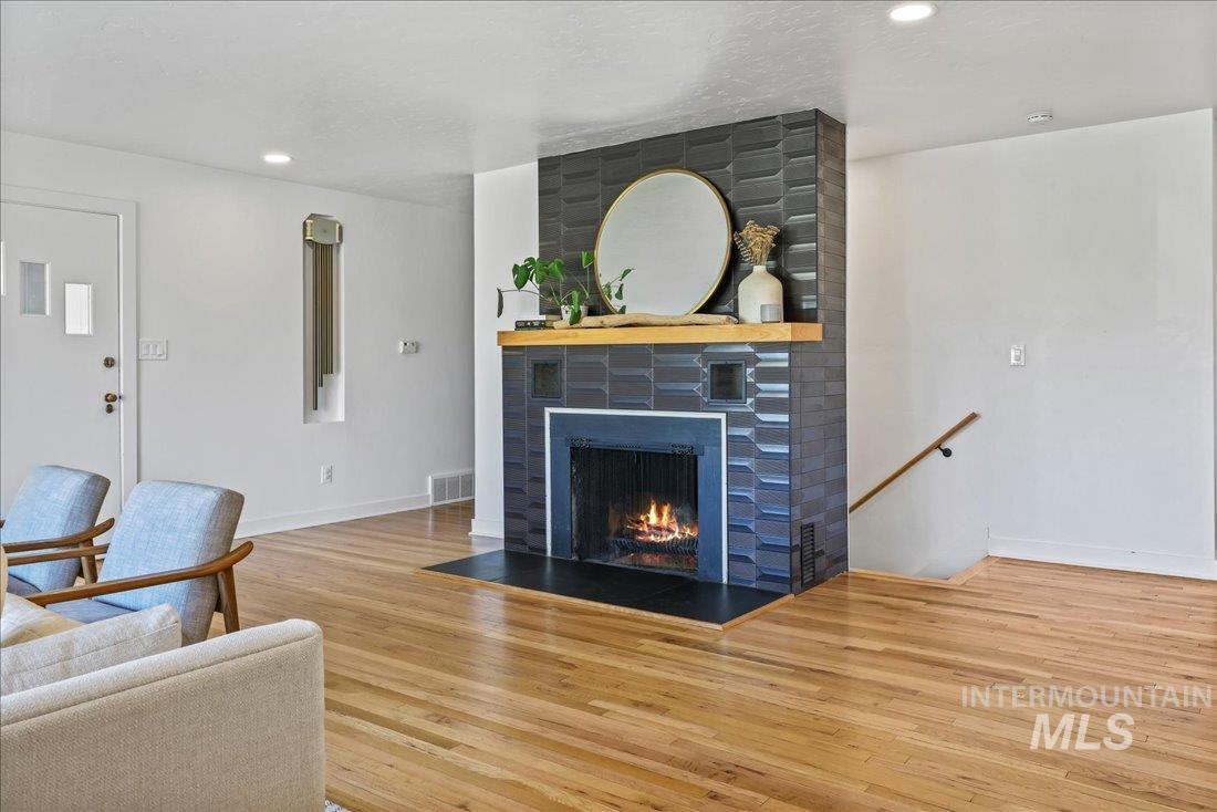Living area with a large fireplace, light wood-style flooring, and recessed lighting