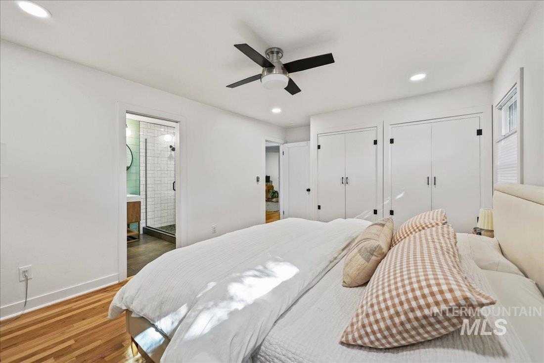 Bedroom with multiple closets, wood finished floors, recessed lighting, a ceiling fan, and ensuite bathroom