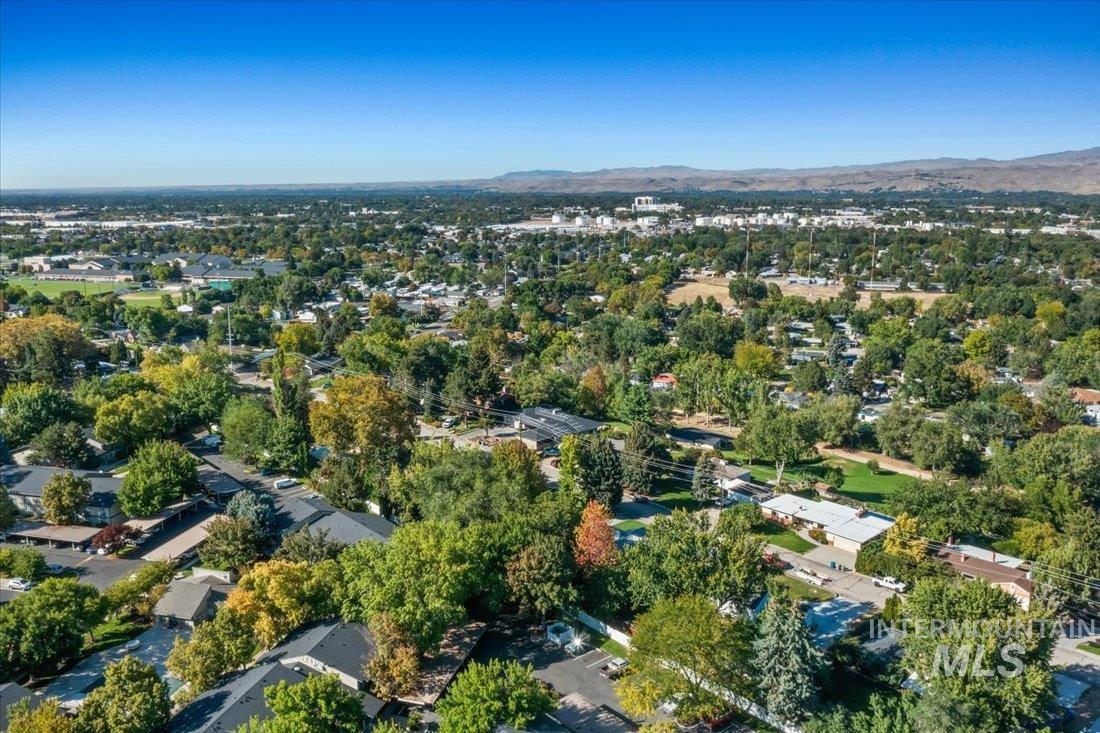 Aerial view of property and surrounding area with a mountain backdrop and a tree filled landscape