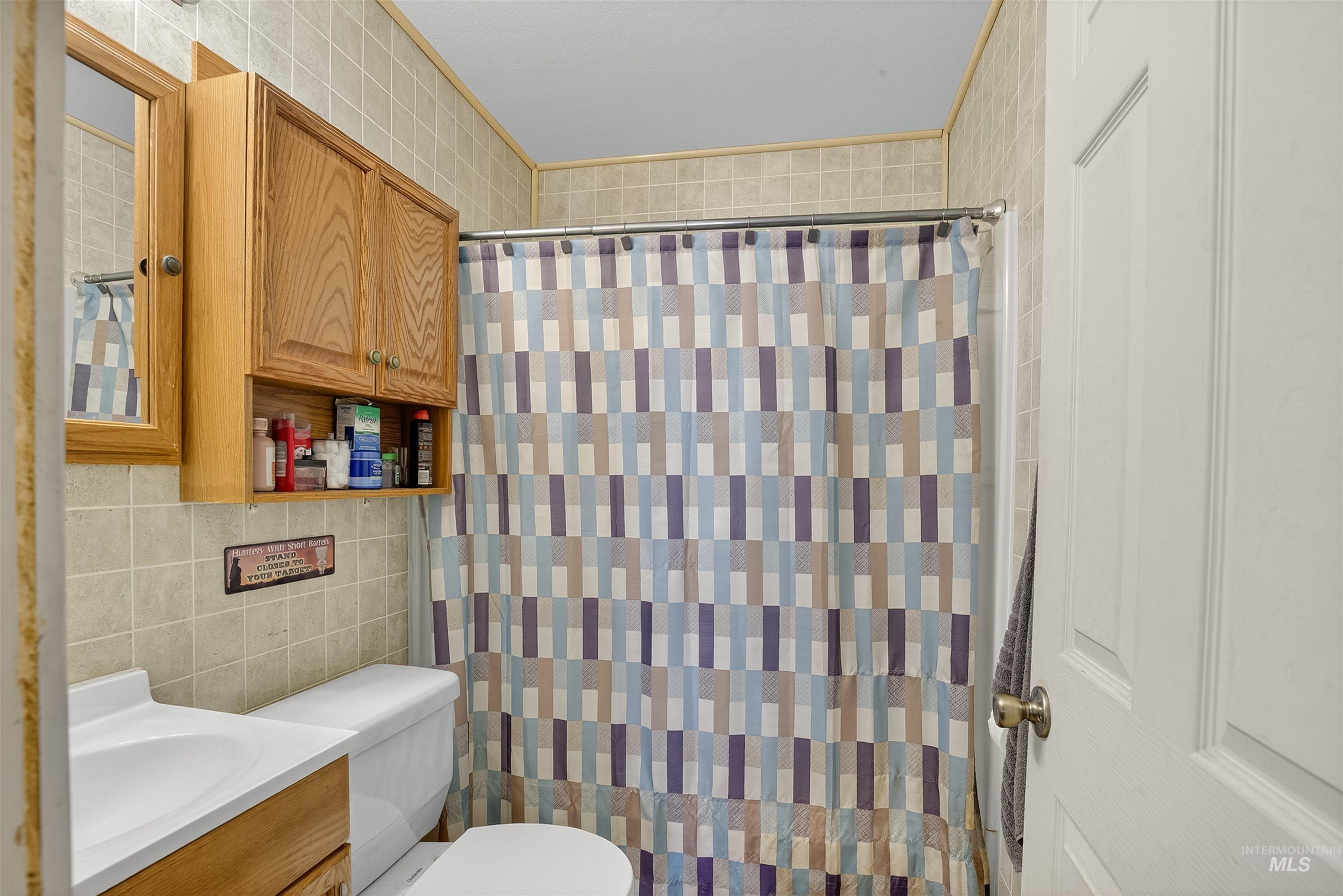 Full bath with tile walls, vanity, and a shower with shower curtain