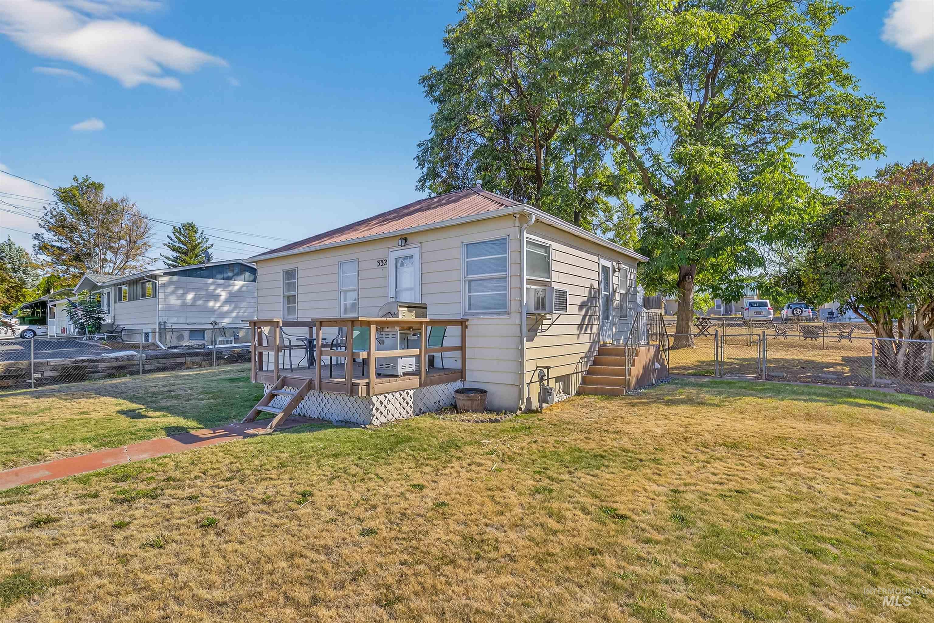 Rear view of property with a metal roof, a fenced backyard, and a deck