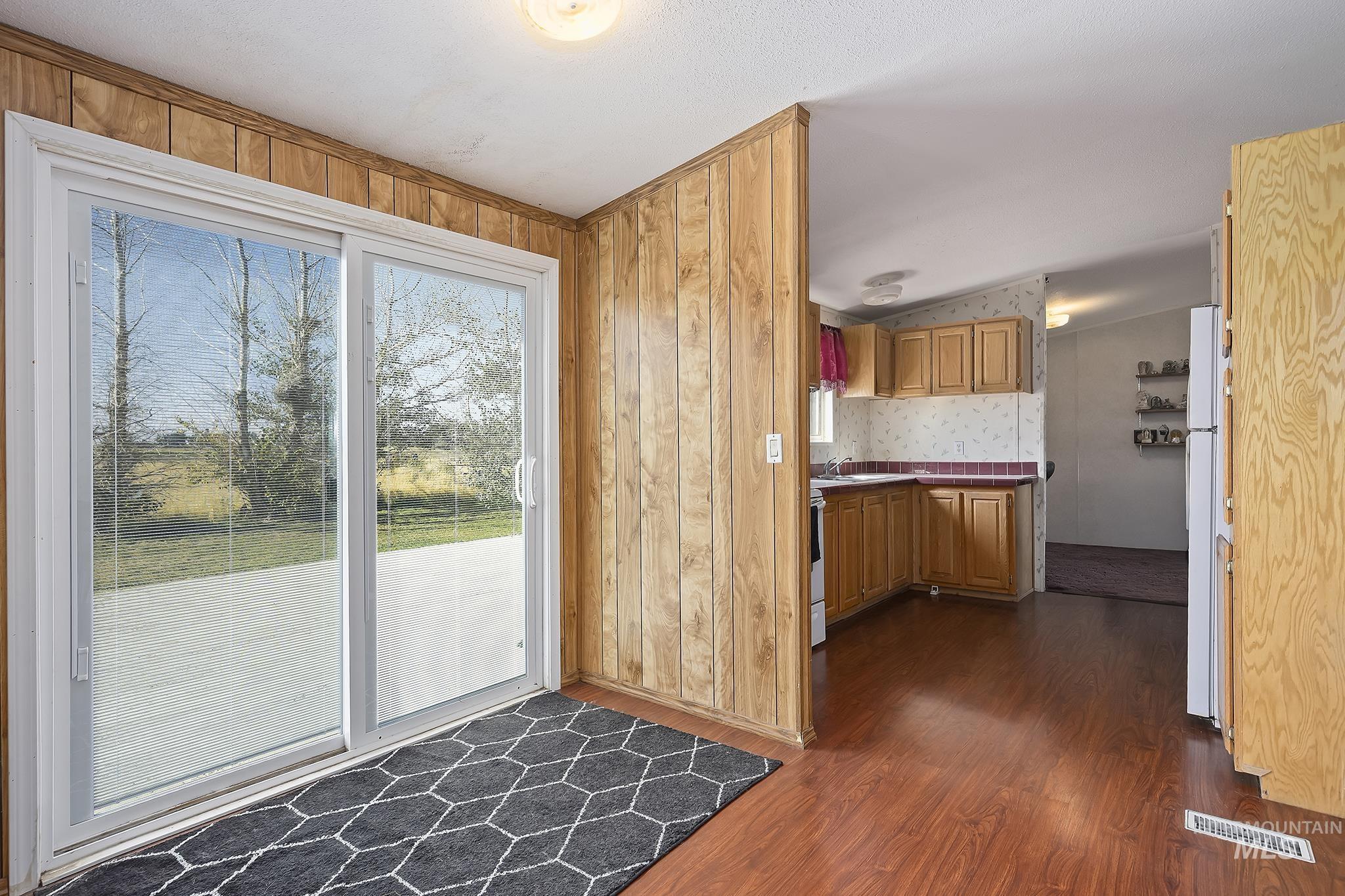 Doorway with wood finished floors and wooden walls