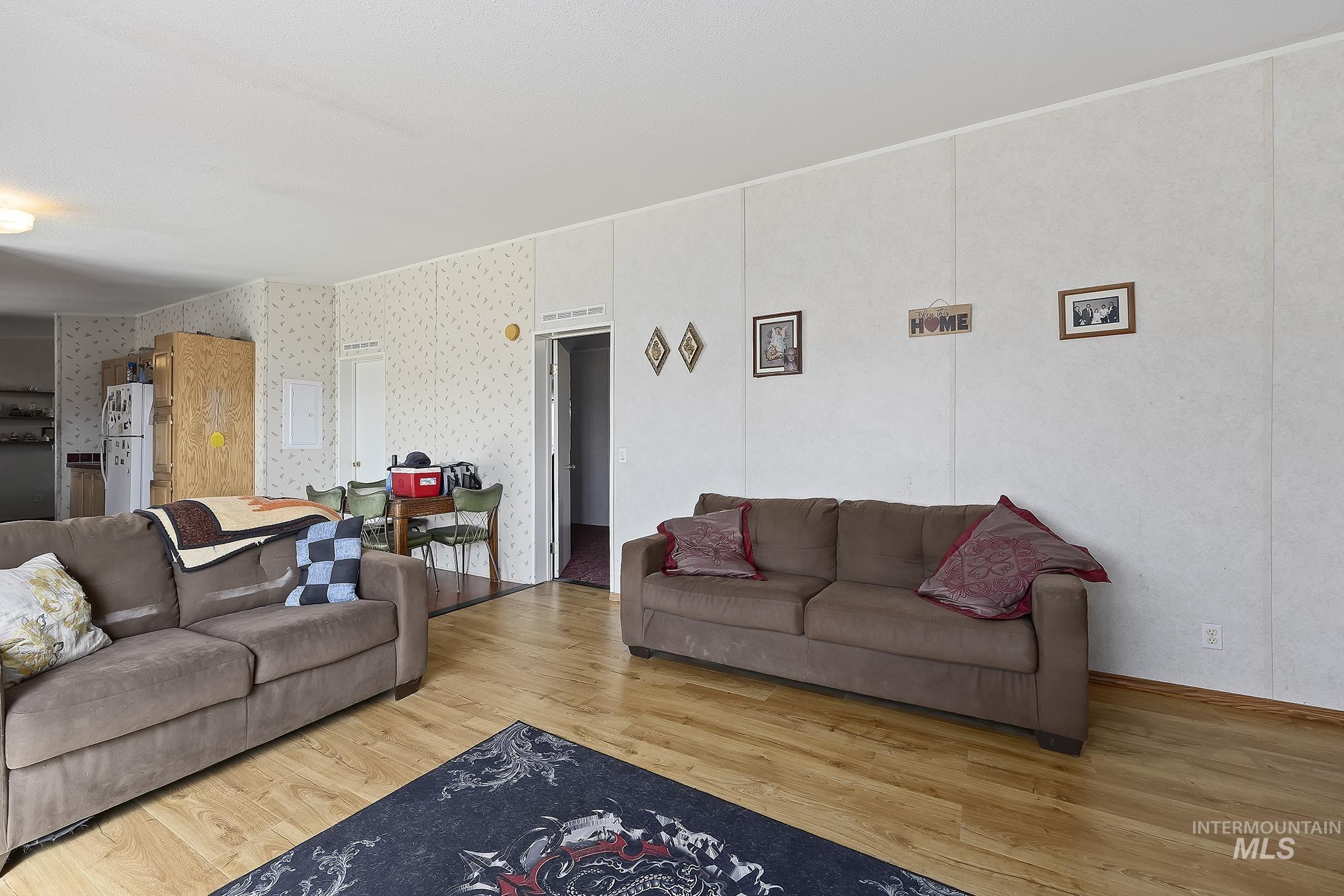 Living room featuring light wood finished floors, wallpapered walls, and electric panel
