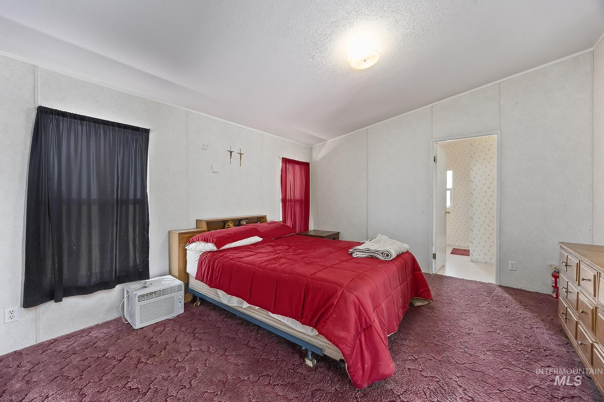 Bedroom with carpet floors, ensuite bathroom, and a textured ceiling