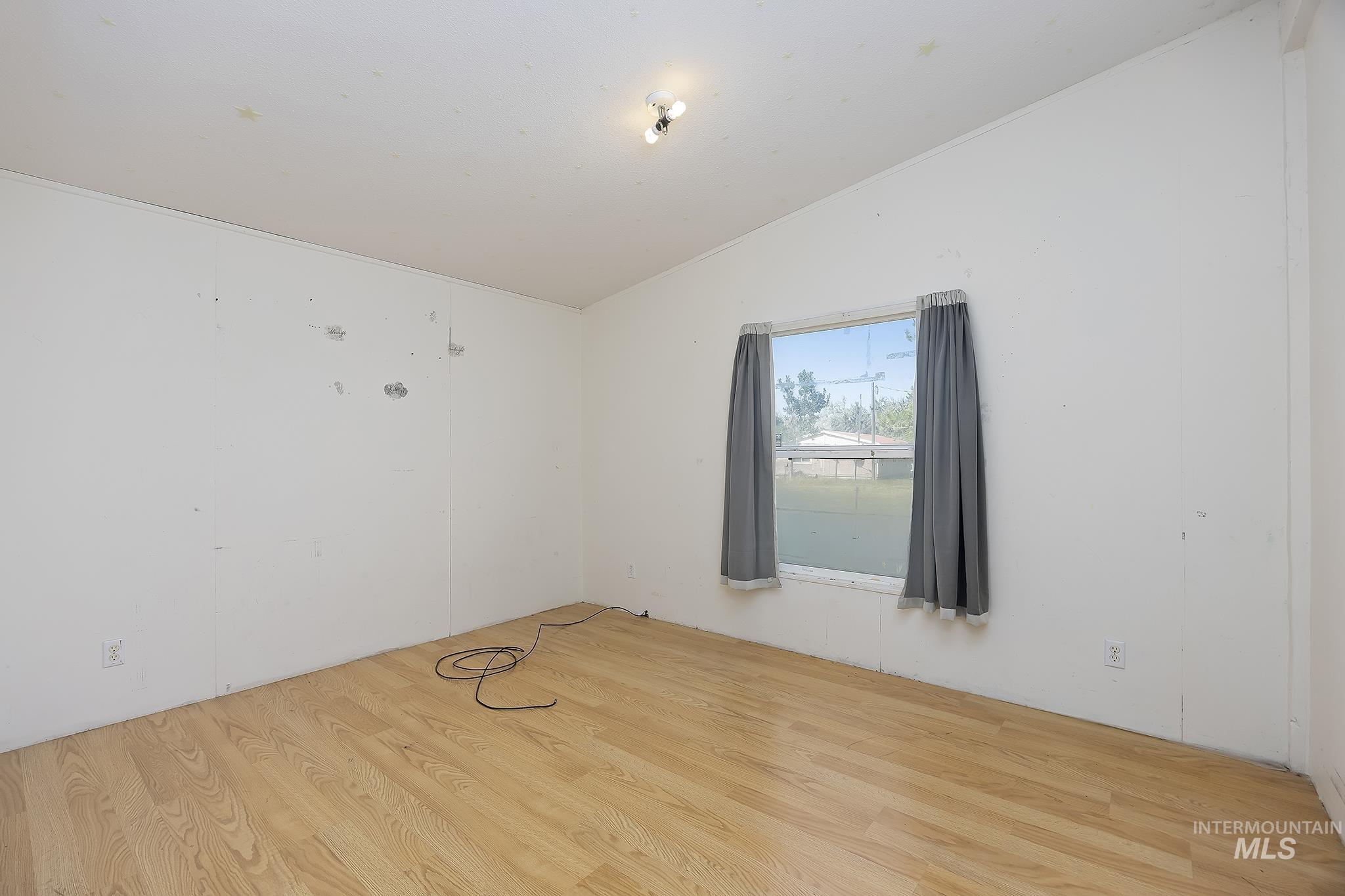 Unfurnished room featuring wood finished floors and lofted ceiling