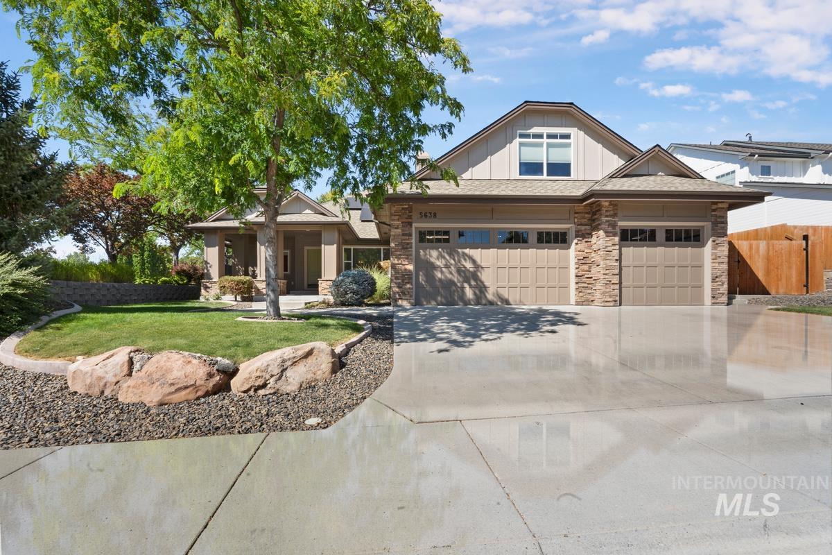 Craftsman house featuring board and batten siding, stone siding, a garage, and concrete driveway