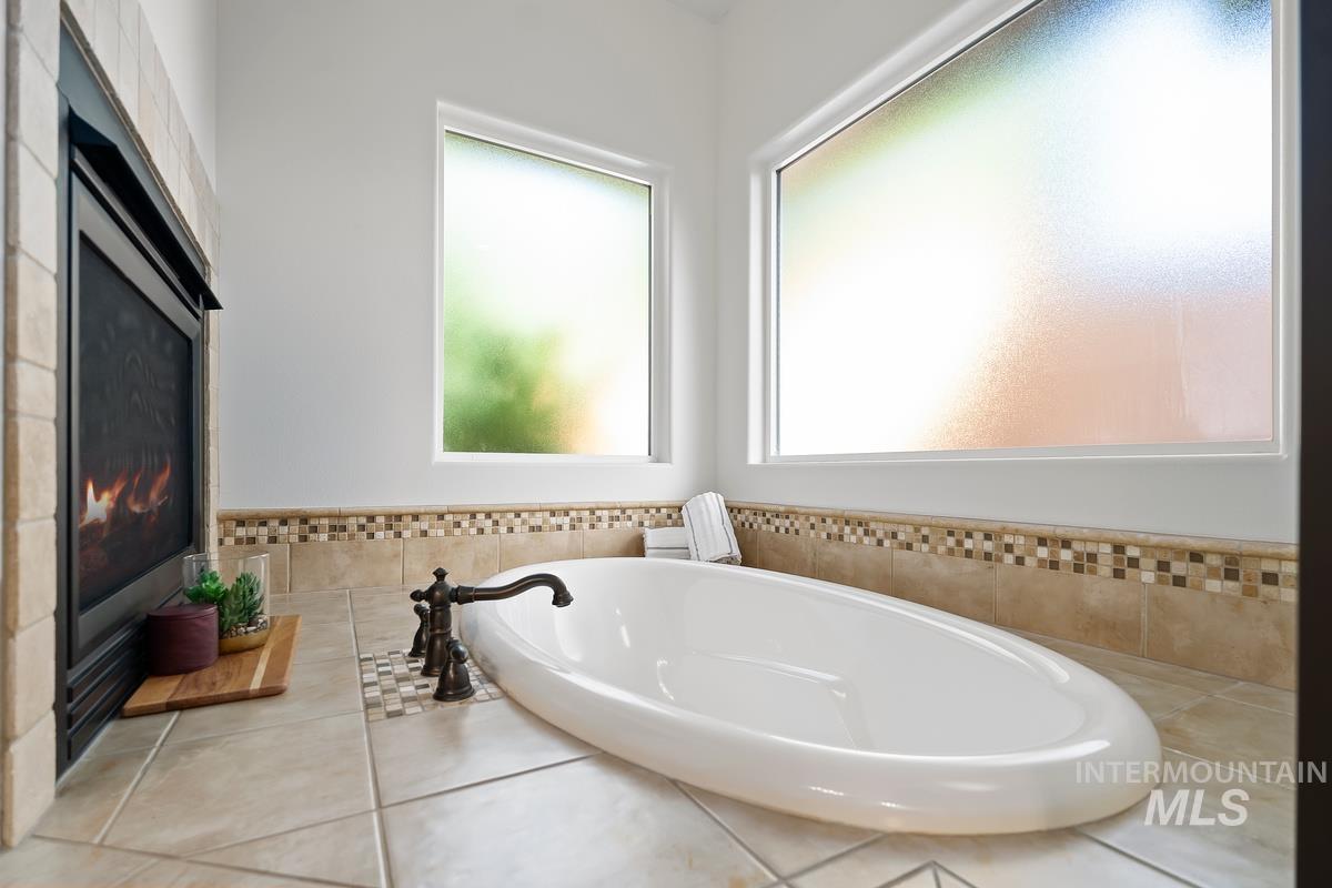 Full bathroom featuring a bath, tile walls, tile patterned flooring, and wainscoting