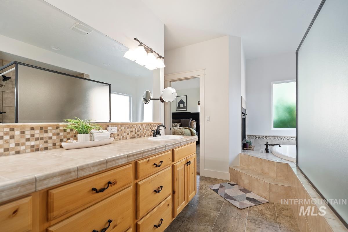 Ensuite bathroom with plenty of natural light, vanity, a shower stall, and a bath