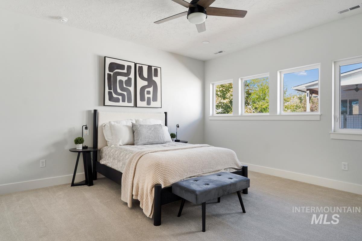 Bedroom featuring light colored carpet, a textured ceiling, and ceiling fan