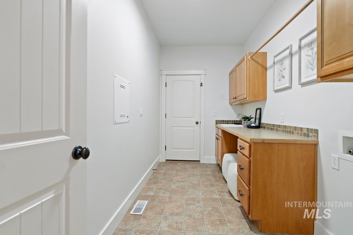 Laundry room with cabinet space, washer hookup, and light tile patterned flooring