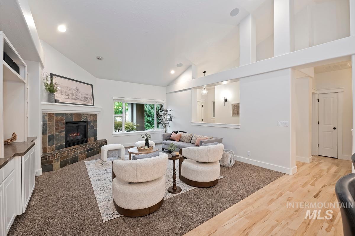 Living area with lofted ceiling, light wood-type flooring, a tile fireplace, and recessed lighting